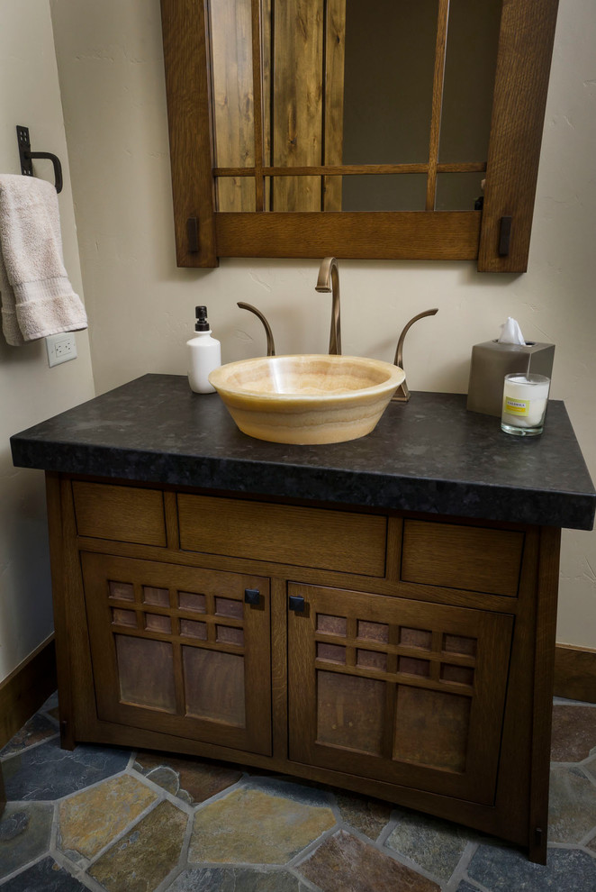 Immagine di un bagno di servizio stile rurale di medie dimensioni con ante in legno bruno, pareti bianche, lavabo a bacinella, top in saponaria, pavimento multicolore e top nero
