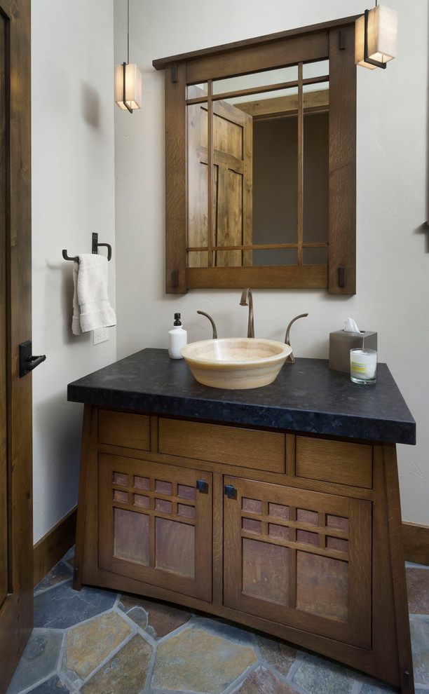 Пример оригинального дизайна: туалет среднего размера в стиле рустика с темными деревянными фасадами, белыми стенами, настольной раковиной, столешницей из талькохлорита, разноцветным полом и черной столешницей