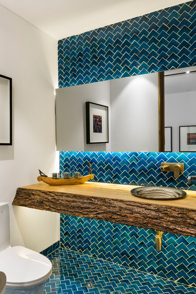 Moderne Gästetoilette mit blauen Fliesen, weißer Wandfarbe, Einbauwaschbecken, Waschtisch aus Holz, blauem Boden und brauner Waschtischplatte in Delhi