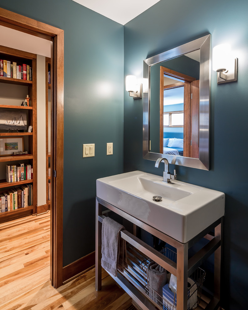 Idee per un piccolo bagno di servizio minimal con nessun'anta, pavimento in legno massello medio, pareti blu e lavabo integrato