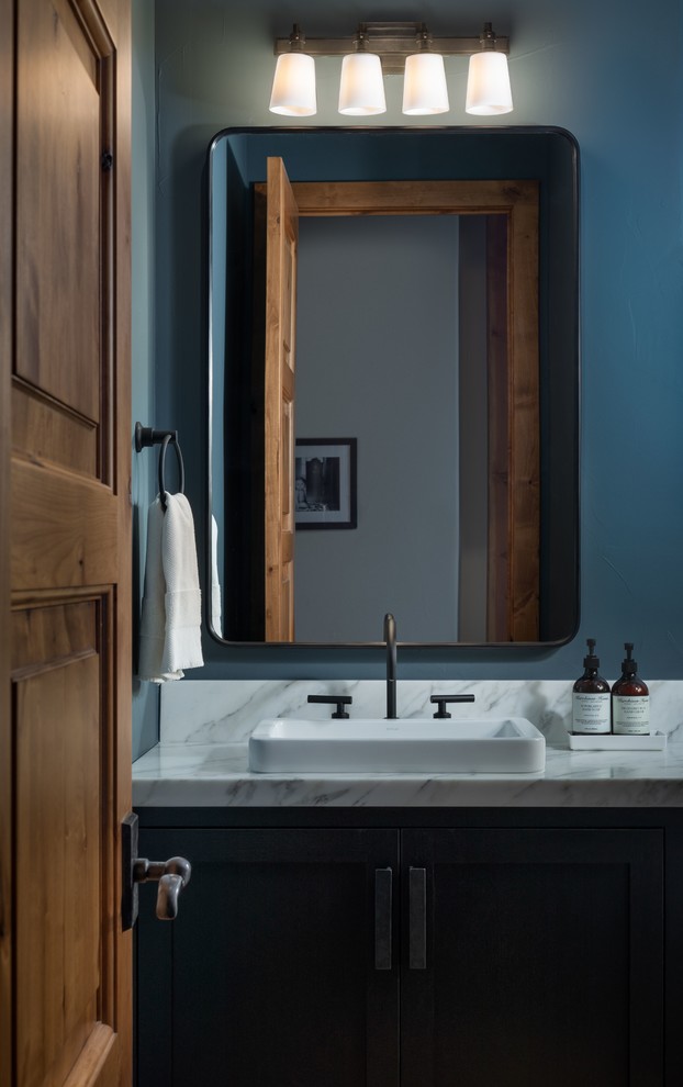 Diseño de aseo tradicional renovado con armarios estilo shaker, puertas de armario negras, paredes azules, lavabo sobreencimera y encimeras blancas
