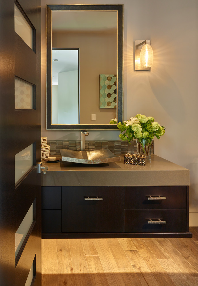 This is an example of a medium sized contemporary cloakroom in San Francisco with flat-panel cabinets, dark wood cabinets, a wall mounted toilet, grey tiles, mosaic tiles, grey walls, dark hardwood flooring, a vessel sink and engineered stone worktops.