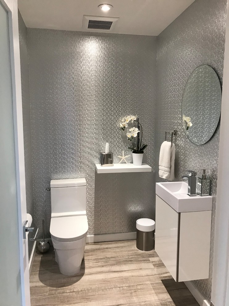 Foto di un piccolo bagno di servizio minimalista con ante bianche, WC monopezzo, pavimento in gres porcellanato, lavabo sospeso, top in quarzite e pavimento marrone