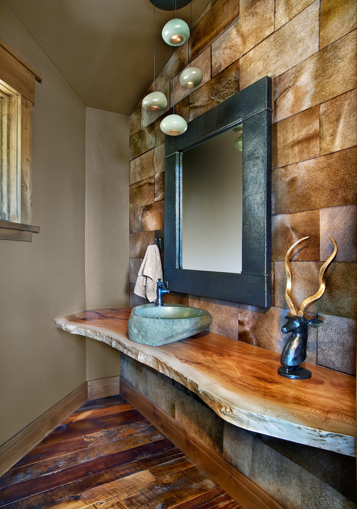 Cette image montre un WC et toilettes chalet avec une vasque, un plan de toilette en bois, un mur marron, parquet foncé et un plan de toilette marron.