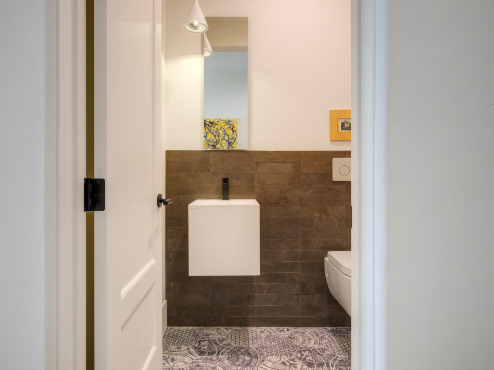 Cette photo montre un WC suspendu de taille moyenne avec un carrelage marron, un carrelage de pierre, un mur blanc, un sol en carrelage de porcelaine et un lavabo suspendu.