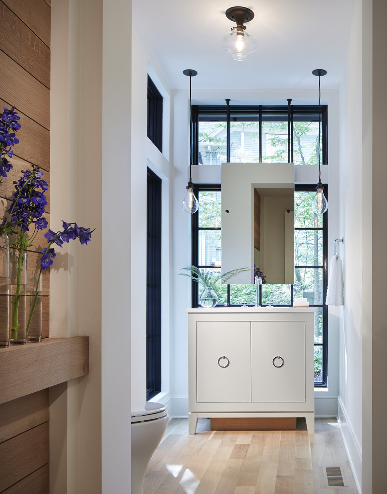Foto de aseo clásico renovado con armarios con paneles lisos, puertas de armario blancas, paredes blancas, suelo de madera clara y lavabo bajoencimera