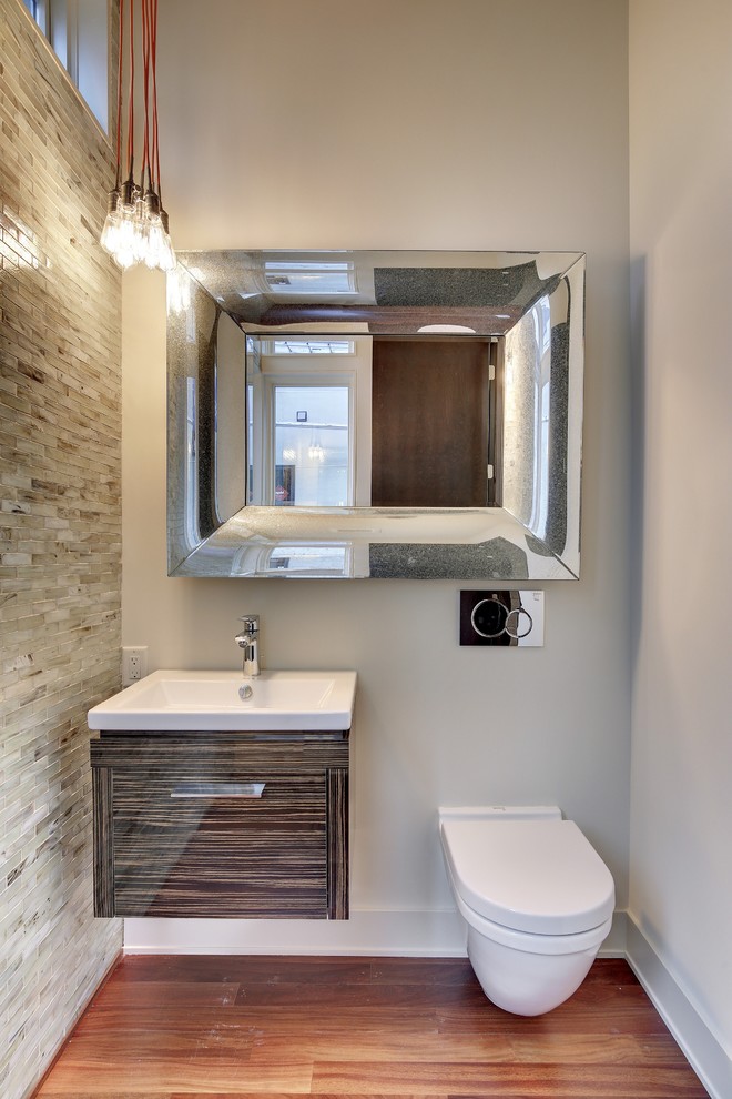 Inspiration for a large modern mosaic tile and gray tile medium tone wood floor powder room remodel in Minneapolis with flat-panel cabinets, a wall-mount toilet, white walls, an integrated sink and dark wood cabinets