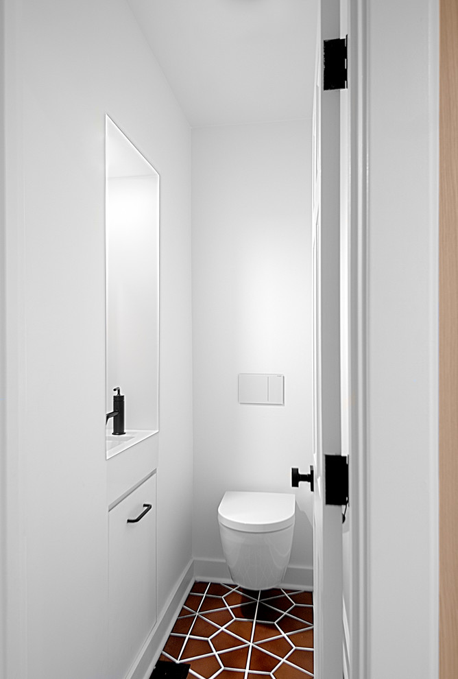 Idee per un piccolo bagno di servizio design con ante lisce, ante bianche, WC sospeso, pareti bianche, pavimento in gres porcellanato, lavabo sottopiano, top in laminato, pavimento marrone e top bianco