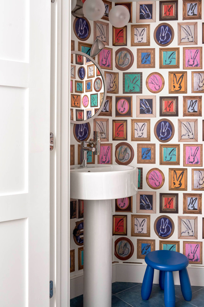 Diseño de aseo bohemio con paredes multicolor, lavabo con pedestal y suelo azul