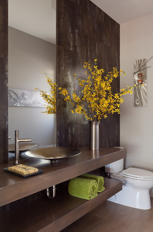 Inspiration for a medium sized contemporary cloakroom in Denver with a vessel sink, open cabinets, a two-piece toilet, medium hardwood flooring, dark wood cabinets, brown worktops, brown tiles, wooden worktops and brown floors.