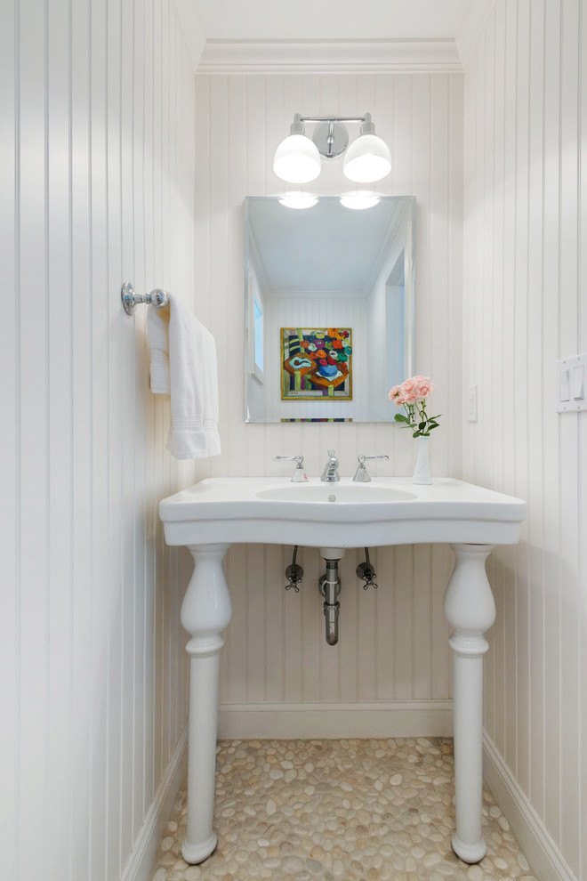 Idee per un piccolo bagno di servizio stile marinaro con lavabo a colonna, WC monopezzo, pareti bianche e pavimento con piastrelle di ciottoli