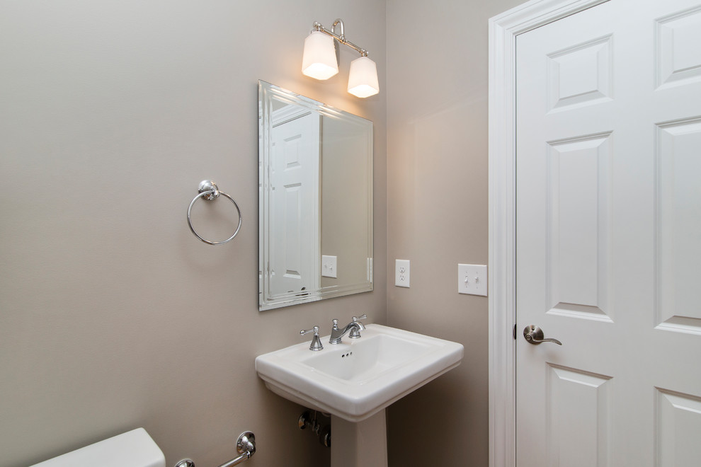 На фото: туалет в стиле кантри с унитазом-моноблоком, серыми стенами, паркетным полом среднего тона и раковиной с пьедесталом
