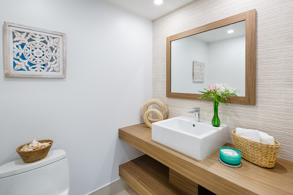 Maritime Gästetoilette mit offenen Schränken, beigen Schränken, Toilette mit Aufsatzspülkasten, weißer Wandfarbe, Aufsatzwaschbecken, Waschtisch aus Holz und brauner Waschtischplatte in Miami