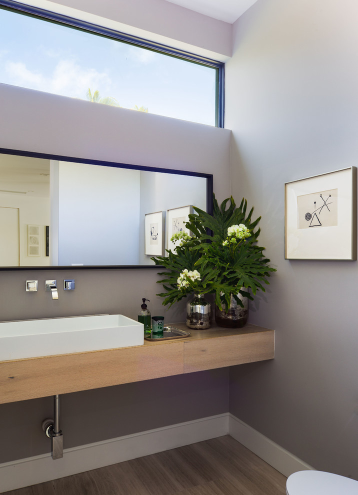 Idées déco pour un WC et toilettes contemporain en bois clair de taille moyenne avec WC à poser, un mur gris, un sol en calcaire, une vasque et un sol beige.