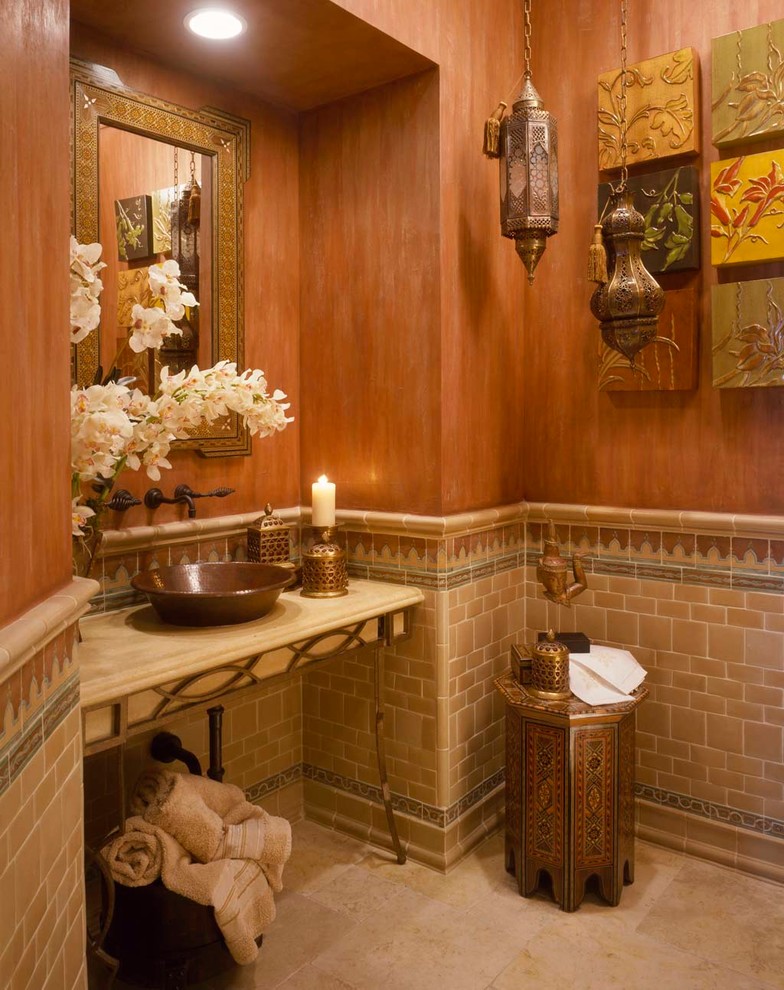 Cette image montre un grand WC et toilettes méditerranéen avec une vasque, un placard en trompe-l'oeil, un plan de toilette en marbre, un carrelage beige, des carreaux de céramique, un mur orange et un sol en marbre.