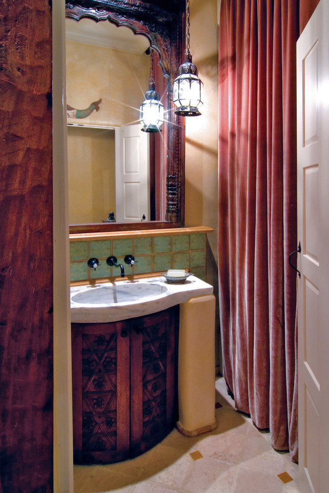 На фото: туалет среднего размера в средиземноморском стиле с монолитной раковиной, фасадами островного типа, фасадами цвета дерева среднего тона, мраморной столешницей, зеленой плиткой, керамической плиткой, полом из травертина и бежевыми стенами