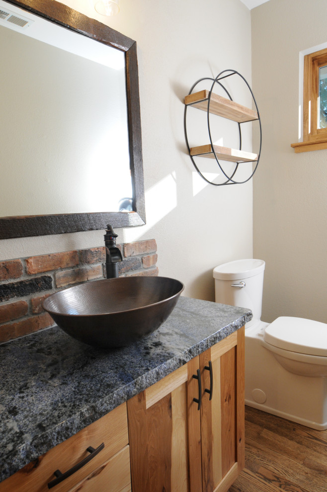 Bild på ett litet rustikt blå blått toalett, med skåp i shakerstil, skåp i ljust trä, en toalettstol med separat cisternkåpa, brun kakel, vita väggar, mörkt trägolv, ett fristående handfat, granitbänkskiva och brunt golv