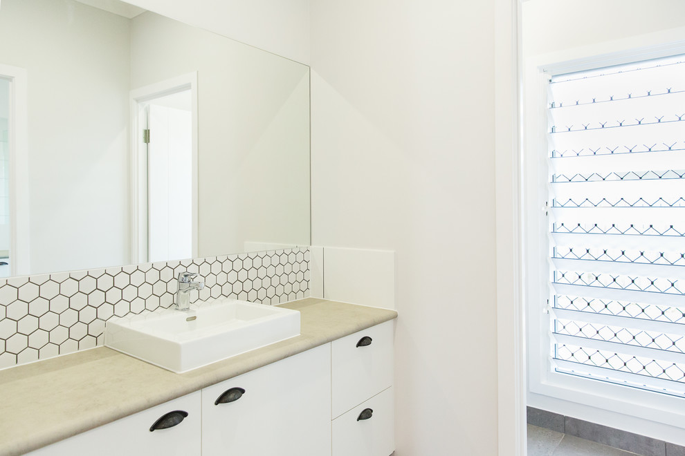 Réalisation d'un WC et toilettes design avec un placard à porte plane, des portes de placard blanches, un carrelage blanc, mosaïque, un mur gris, une vasque, un plan de toilette en stratifié, un plan de toilette gris, un sol en carrelage de céramique et un sol gris.