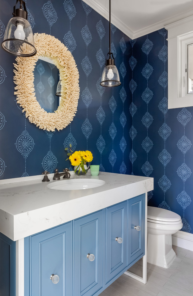 Idée de décoration pour un petit WC et toilettes champêtre avec un placard avec porte à panneau encastré, des portes de placard bleues, un mur bleu, un sol en carrelage de porcelaine, un lavabo encastré, un plan de toilette en quartz modifié, un sol gris et un plan de toilette blanc.