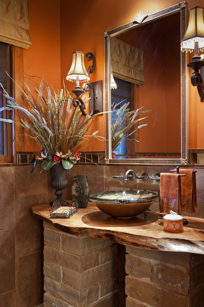 Urige Gästetoilette mit Aufsatzwaschbecken, Waschtisch aus Holz, Steinfliesen und brauner Waschtischplatte in Orange County