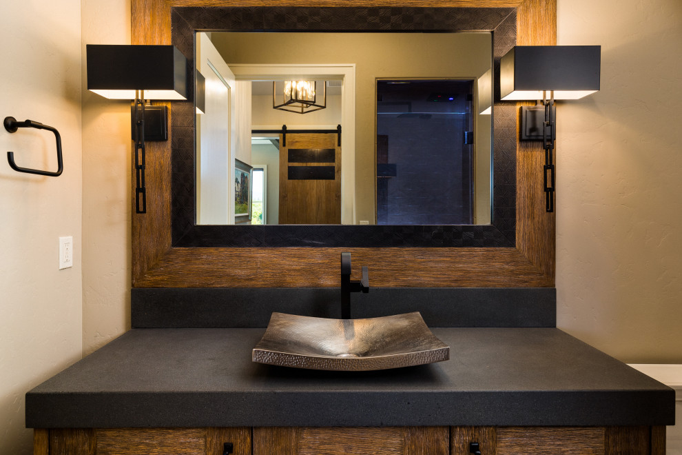 Example of a mid-sized mountain style black tile and ceramic tile medium tone wood floor and brown floor powder room design in Other with recessed-panel cabinets, distressed cabinets, a two-piece toilet, beige walls, a vessel sink, concrete countertops, black countertops and a built-in vanity