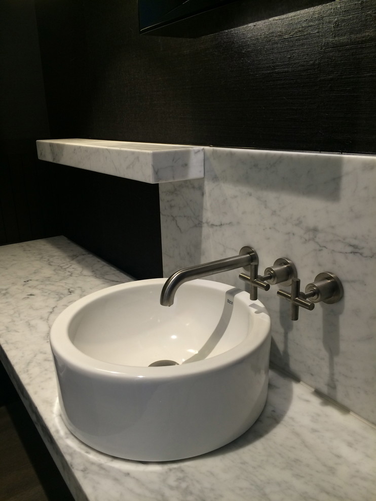 Esempio di un piccolo bagno di servizio minimalista con lavabo a bacinella, consolle stile comò, top in marmo e pareti nere