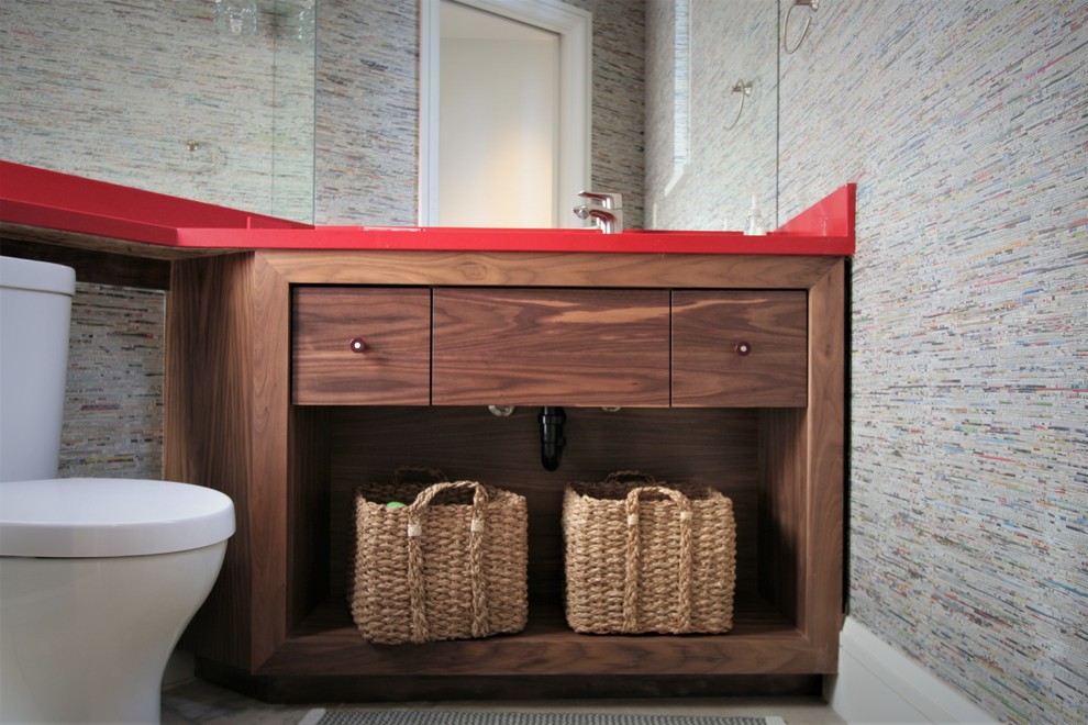 Réalisation d'un petit WC et toilettes design en bois brun avec un placard sans porte, WC à poser, un lavabo encastré, un plan de toilette en surface solide et un mur gris.
