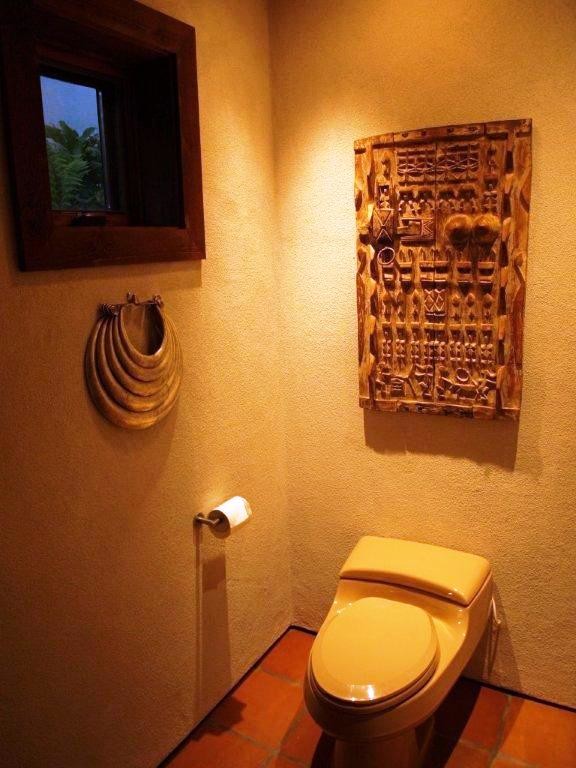 Aménagement d'un WC et toilettes asiatique de taille moyenne avec WC à poser, un mur beige, tomettes au sol et un sol marron.
