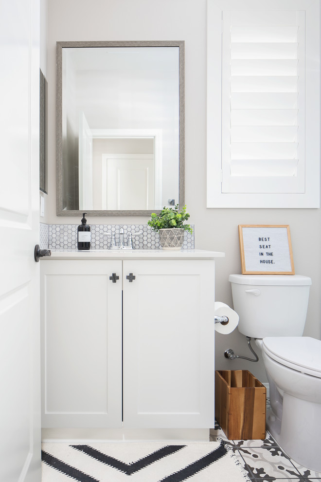 Klassische Gästetoilette mit Schrankfronten im Shaker-Stil, weißen Schränken, grauer Wandfarbe, buntem Boden und weißer Waschtischplatte in Sonstige
