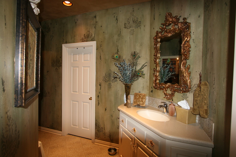 На фото: туалет среднего размера в средиземноморском стиле с фасадами с выступающей филенкой, белыми фасадами, зелеными стенами, полом из керамической плитки, врезной раковиной, столешницей из искусственного камня и бежевым полом