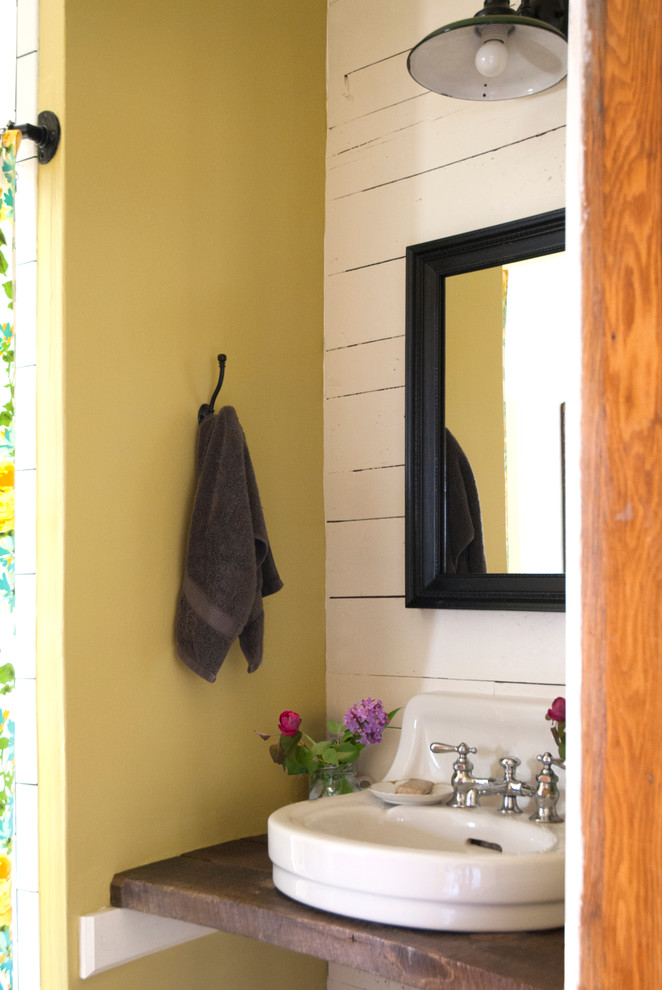 Exemple d'un petit WC et toilettes éclectique avec une vasque, un plan de toilette en bois, un mur jaune et un plan de toilette marron.