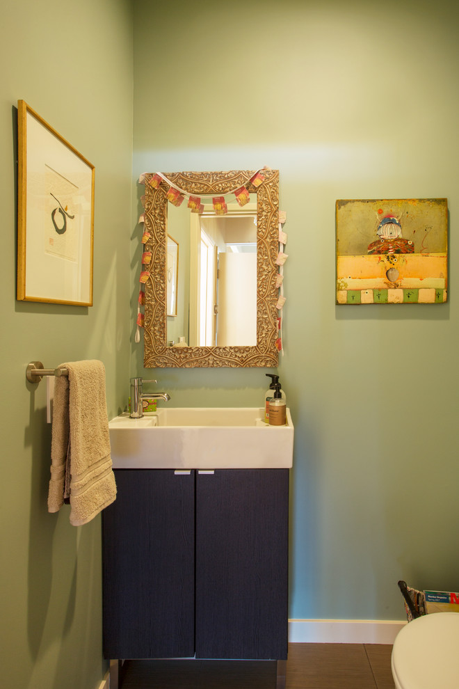 Bild på ett eklektiskt toalett, med släta luckor, bruna skåp och gröna väggar