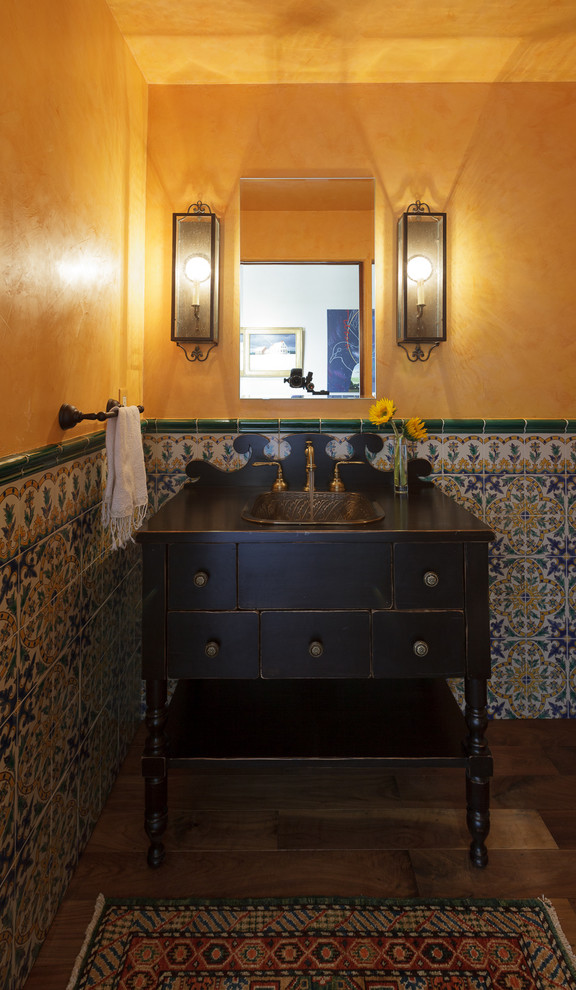Design ideas for a small mediterranean cloakroom in Orange County with freestanding cabinets, dark wood cabinets, blue tiles, cement tiles, yellow walls, a built-in sink, wooden worktops and brown floors.
