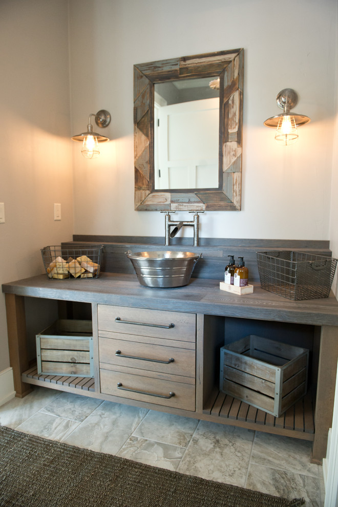 Cette image montre un WC et toilettes rustique en bois brun de taille moyenne avec un placard à porte plane, un mur gris, un sol en carrelage de céramique, une vasque, un plan de toilette en zinc et un sol gris.