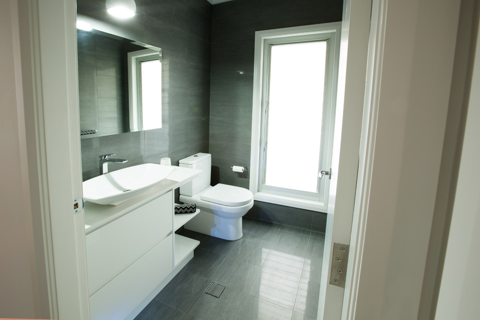 This is an example of a contemporary cloakroom in Sydney with a vessel sink, flat-panel cabinets, white cabinets, engineered stone worktops, a one-piece toilet, grey tiles, porcelain tiles, grey walls and porcelain flooring.