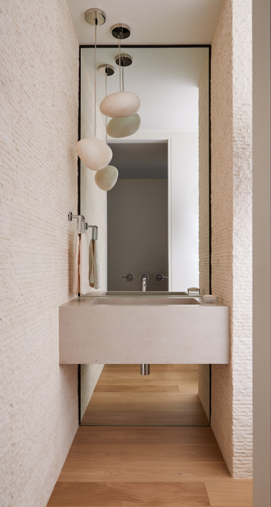 Réalisation d'un WC et toilettes minimaliste avec un carrelage blanc, un carrelage de pierre, un sol en bois brun, un lavabo intégré, un sol marron et un plan de toilette gris.