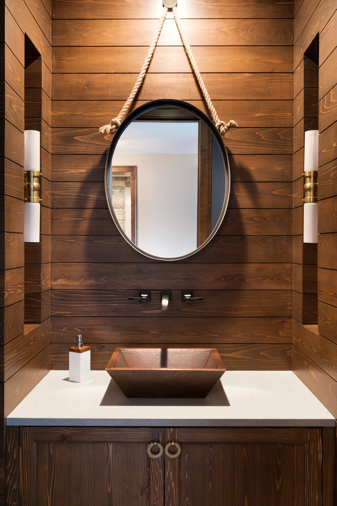 Example of a beach style powder room design in Minneapolis with recessed-panel cabinets, dark wood cabinets, brown walls, a vessel sink and white countertops