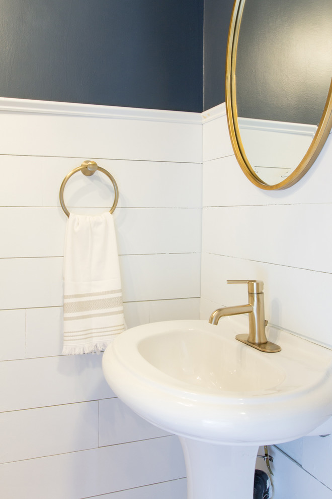 Idee per un piccolo bagno di servizio stile marinaro con WC a due pezzi, pareti blu, pavimento in bambù, lavabo a colonna e pavimento marrone