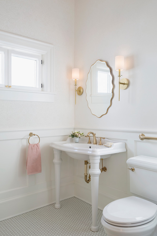 Klassisk inredning av ett litet toalett, med luckor med infälld panel, vita skåp, en toalettstol med separat cisternkåpa, vita väggar, vitt golv, mosaikgolv och ett väggmonterat handfat