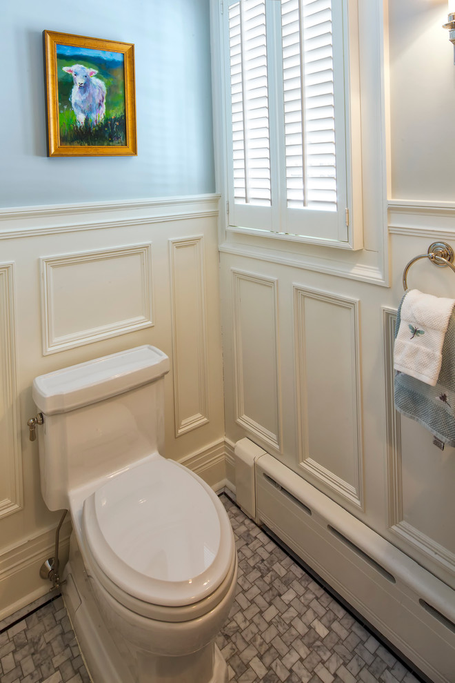 На фото: туалет в классическом стиле с белыми фасадами, унитазом-моноблоком, синими стенами, мраморным полом и подвесной раковиной