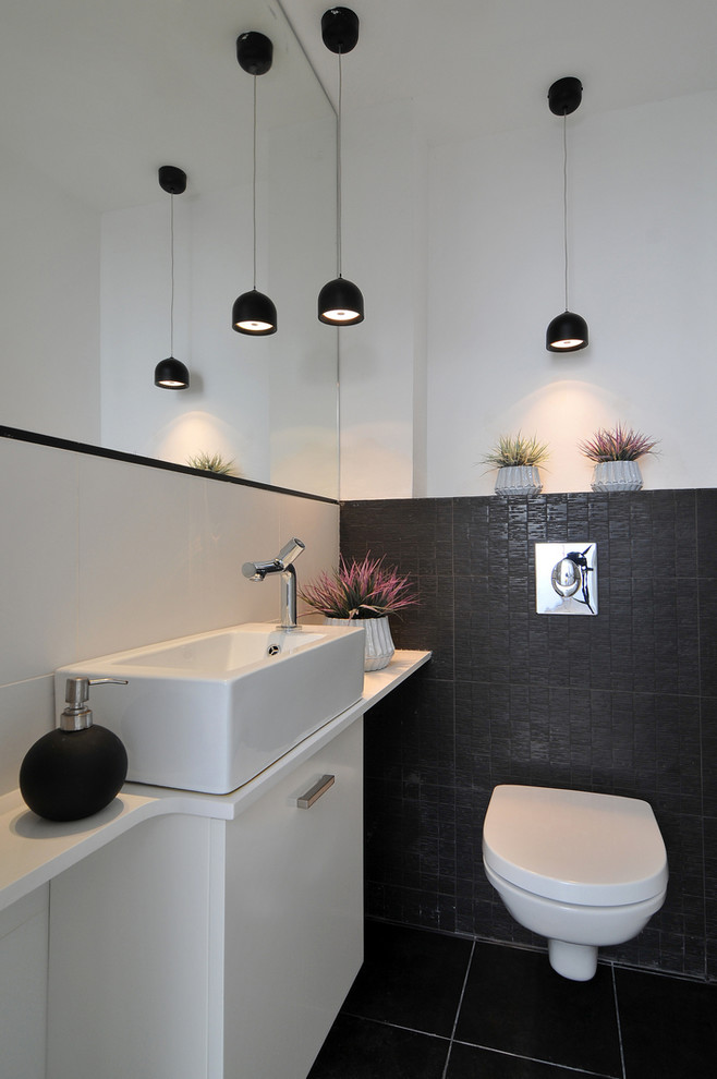 Свежая идея для дизайна: туалет в современном стиле с настольной раковиной, плоскими фасадами, белыми фасадами, инсталляцией, черной плиткой, белыми стенами и белой столешницей - отличное фото интерьера