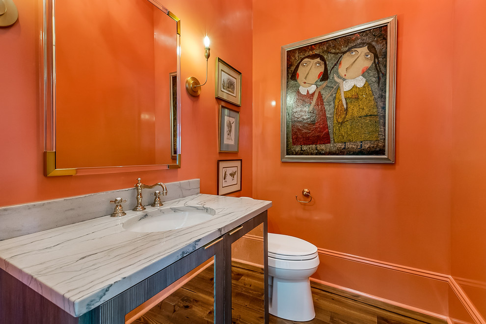 Aménagement d'un petit WC et toilettes contemporain avec WC à poser, un mur orange, un sol en bois brun, un lavabo encastré, un plan de toilette en quartz, un sol marron et un plan de toilette gris.