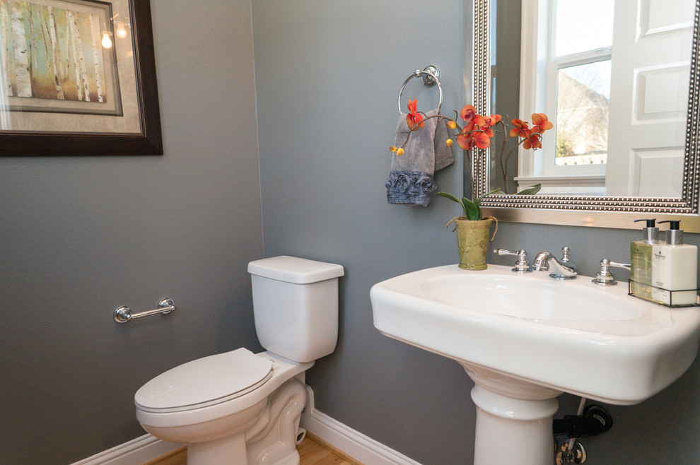 Idéer för ett mellanstort klassiskt toalett, med ett piedestal handfat, grå väggar och ljust trägolv