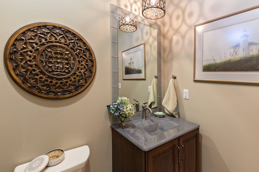 Idée de décoration pour un WC et toilettes tradition en bois foncé avec un placard avec porte à panneau surélevé, un carrelage gris, un mur beige et un lavabo intégré.
