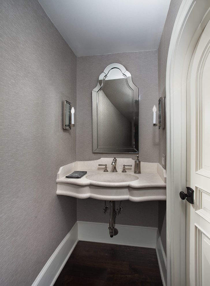 Kleine Klassische Gästetoilette mit grauer Wandfarbe, dunklem Holzboden, Wandwaschbecken, Kalkstein-Waschbecken/Waschtisch und braunem Boden in Houston