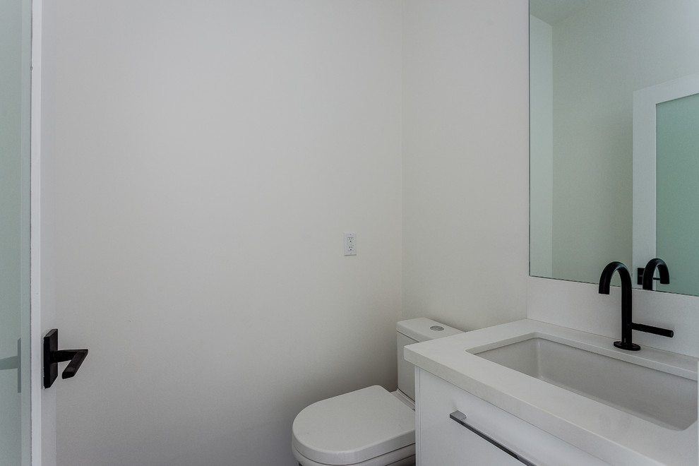 Photo of a medium sized modern cloakroom in Los Angeles with flat-panel cabinets, white cabinets, a two-piece toilet, white walls, a submerged sink, engineered stone worktops and white worktops.