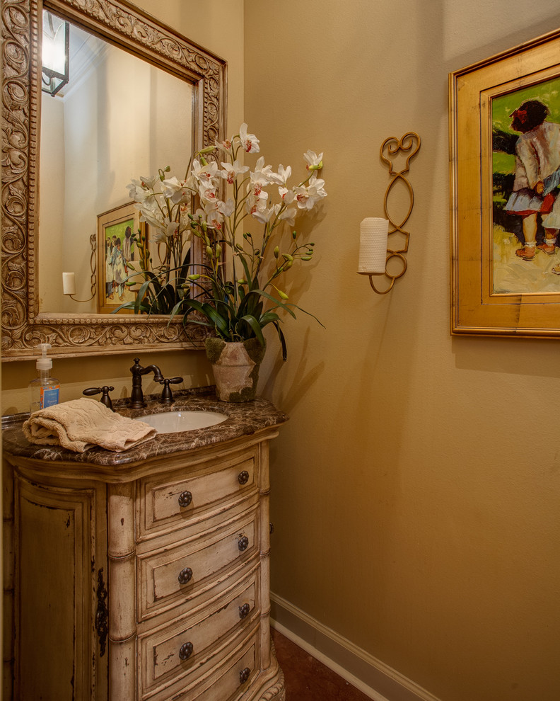 Mittelgroße Klassische Gästetoilette mit profilierten Schrankfronten, beigen Schränken, beiger Wandfarbe, Betonboden, Unterbauwaschbecken und braunem Boden in Little Rock