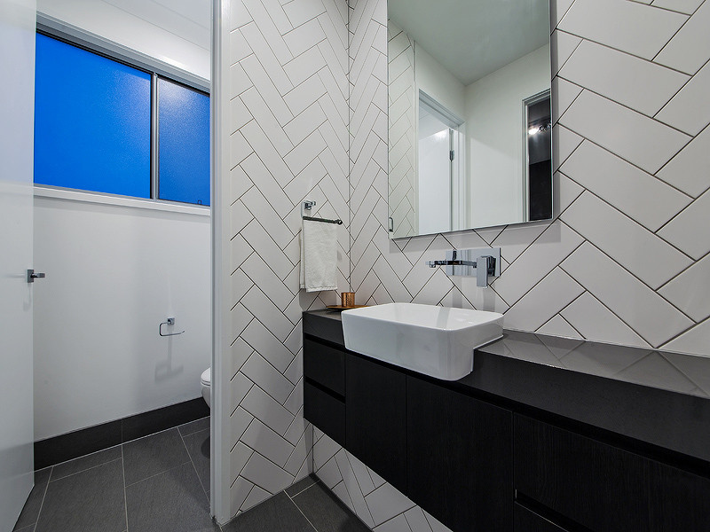 Exemple d'un petit WC et toilettes tendance en bois foncé avec un placard à porte plane, WC séparés, un carrelage blanc, des carreaux de céramique, un mur blanc, un sol en carrelage de céramique, une grande vasque, un plan de toilette en granite et un sol gris.