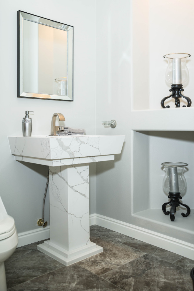 Ejemplo de aseo clásico con sanitario de una pieza, paredes grises, suelo de mármol, lavabo con pedestal, encimera de cuarcita, suelo negro y encimeras blancas