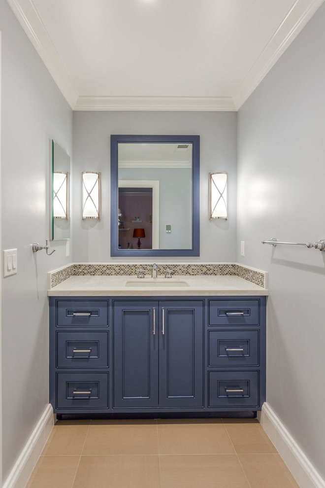 Пример оригинального дизайна: туалет среднего размера в стиле неоклассика (современная классика) с унитазом-моноблоком, плиткой из листового стекла, врезной раковиной, бежевым полом, фасадами с утопленной филенкой, коричневыми фасадами, бежевой плиткой, мраморной столешницей, синими стенами и бежевой столешницей